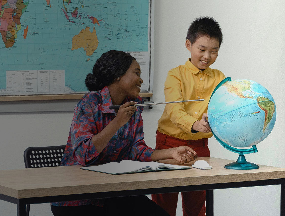 Teacher showing student a globe in a classroom
